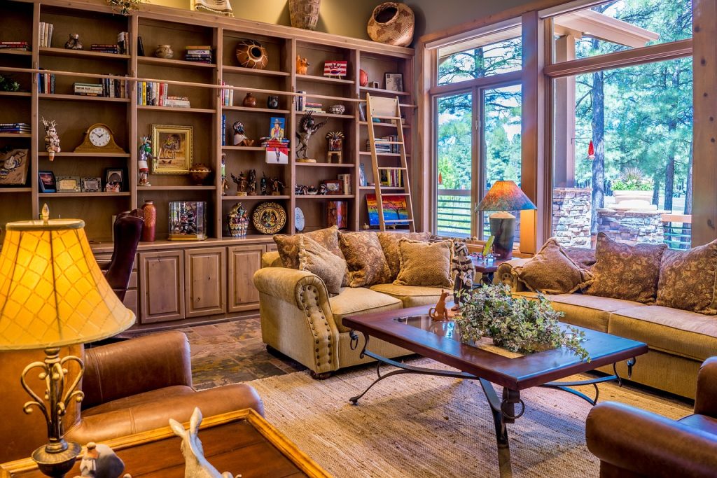 Cosy living room with bookshelf, stylish sofas, and large windows overlooking a lush forest setting