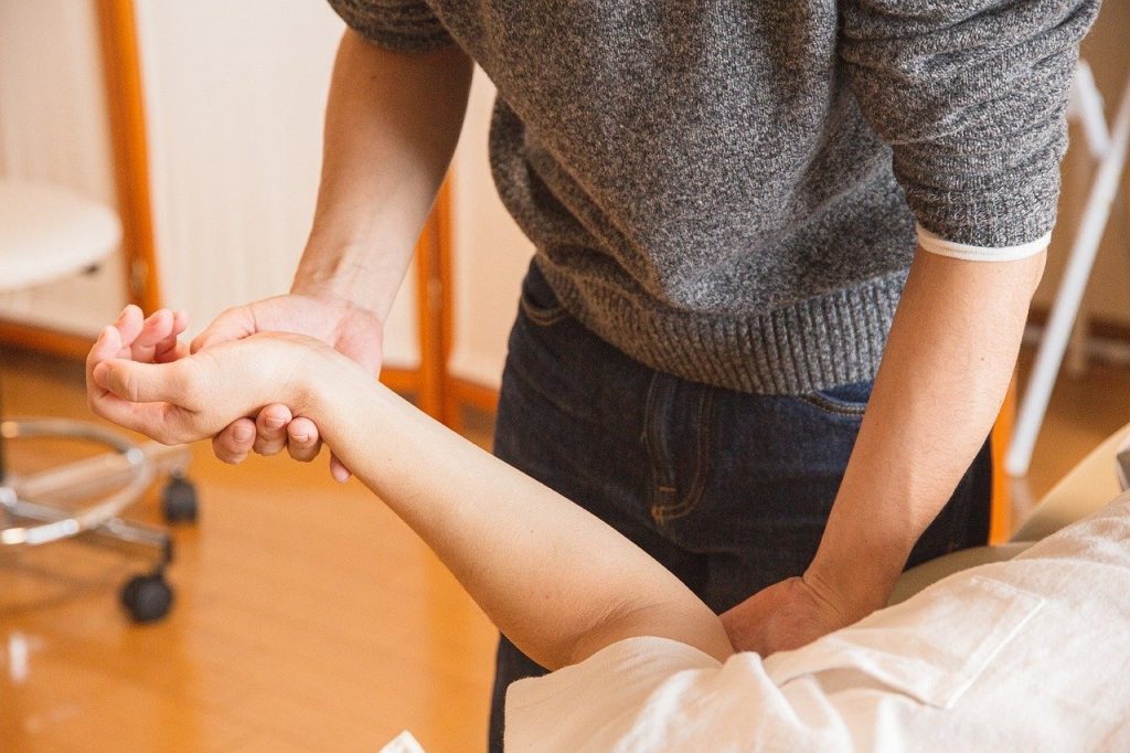 Person performing arm rehabilitation therapy in a clinic, focusing on recovery and wellness.